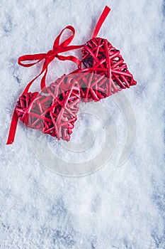 Two beautiful vintage red hearts tied together with a ribbon on a white snow background. Love and St. Valentines Day concept.