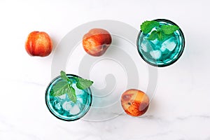 Two beautiful vintage turquoise glasses with cold drink and ice cubes, decorated with fresh green mint leaves and three