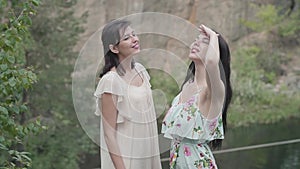 Two beautiful woman in short white dresses standing aroung amazing nature, looking in the sky. Spectacular view. Slow