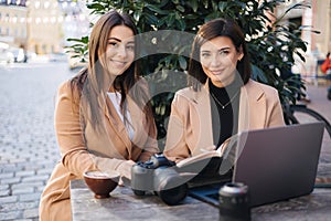 Two beautiful woman sitting in cafe and working. Woman checking free dates and planing. Professional photography career