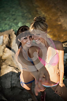 Two beautiful women in bikinis relaxing on beach