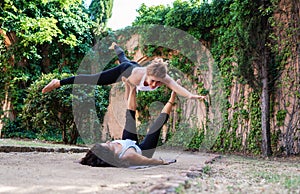 Two beautiful women doing acroyoga in the garden or park