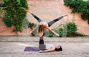 Two beautiful women doing acroyoga in the garden or park