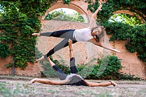 Two beautiful women doing acroyoga in the garden or park