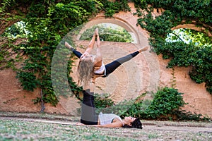 Two beautiful women doing acroyoga in the garden or park