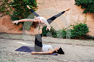 Two beautiful women doing acroyoga in the garden or park