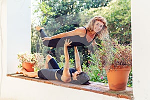 Two beautiful women doing acroyoga in the garden or park