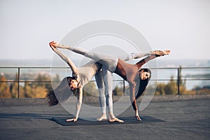 Two beautiful women doing yoga asana Ardha Chandrasana