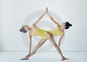 Two beautiful women doing yoga asana extended triangle pose