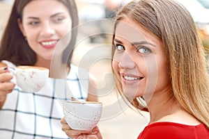 Two beautiful women drinking coffee at outside bar