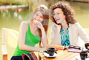 Two beautiful women laughing over a cofee