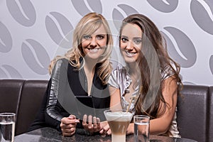 Two beautiful women laughing over a coffee