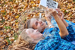 Two beautiful women lying on leaves and reading books in autumn park. Education, friendship lifestyle concept