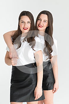 Two beautiful women twin sisters posing white background