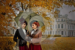 Two beautiful women with umbrellas in the park