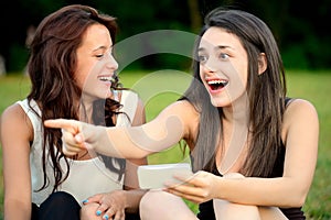 Two beautiful young amazed women pointing outside