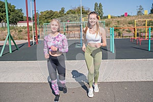 Two beautiful, young and athletic girls running on a street playground.