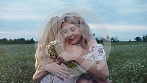 Two beautiful young blonde women hugging in the field