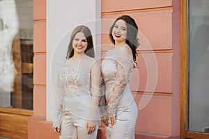 Two beautiful young Caucasian females posing outdoors in an elegant jumpsuit