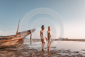 Two beautiful young fashion models on the beach at sea boat