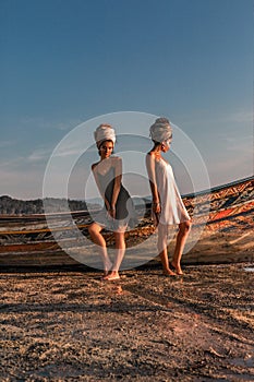 Two beautiful young fashion models on the beach at sea boat