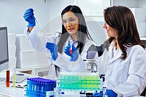 Two beautiful young female scientists working in laboratory with test tubes doing some research