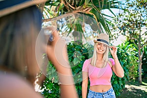 Two beautiful and young girl friends together having fun at the city taking pictures with vintage camera