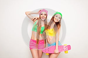 Two beautiful and young girlfriends having fun with a skateboard