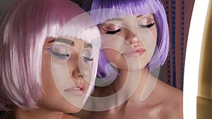 Two beautiful young girls model posing in a pink and purple short bob wig, rhinestones on eyes and stylish pink makeup
