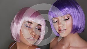 Two beautiful young girls model posing in a pink and purple short bob wig, rhinestones on eyes and stylish pink makeup