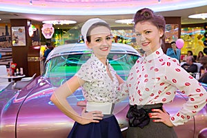 Two beautiful young girls in retro dress have a