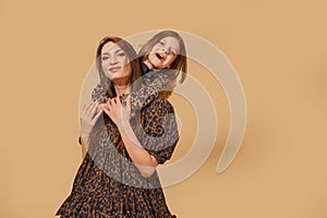 Two beautiful young girls sisters in nice animal pattern dresses with straw hats posing in studio