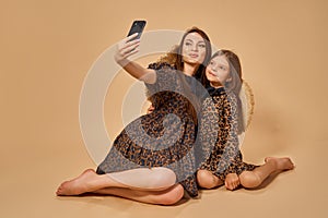 Two beautiful young girls sisters take selfies in nice animal pattern dresses with straw hats posing in studio