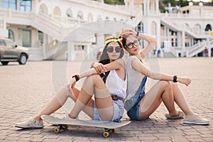 Two beautiful young girls on a skateboard in the city.