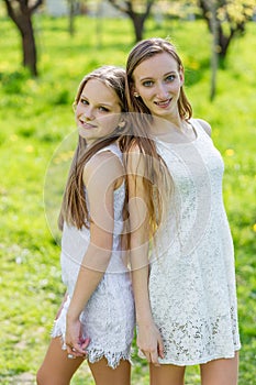 Two beautiful young girls in white dresses in summer