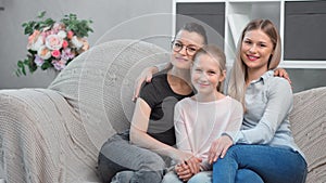 Two beautiful young mother hugging kissing cute teenage girl enjoying parenthood looking at camera