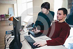 Two beautiful young office workers looking at a computer monitor and discuss the project. The situation in the office.
