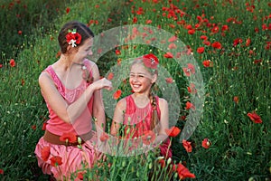 Two beautiful young sisters walking in poppy field