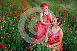 Two beautiful young sisters walking in poppy field