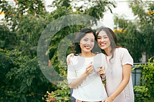 Two beautiful young well-dressed women chatting outdoors over co