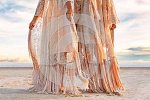 Two beautiful young woman in elegant boho dresses oudoors at sunset