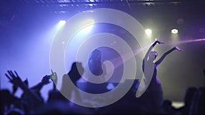 Two beautiful young women DJ play the music on the mixing console in the nightclub. Against the background of unrecognizable peopl