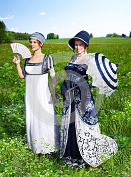 Two beautiful young women dressed in Victorian Regency Jane Austen style fashion dresses