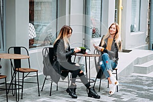 Two beautiful young women drinking tea and gossiping in nice restaurant outdoor .