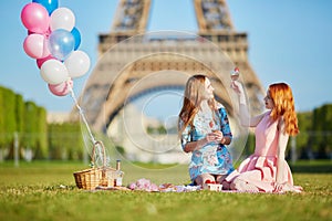 Two young women having picnic near the Eiffel tower in Paris, France