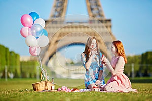 Two young women having picnic near the Eiffel tower in Paris, France