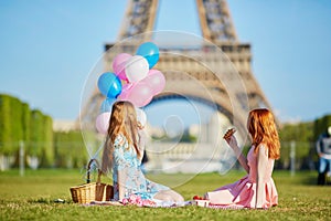 Two young women having picnic near the Eiffel tower in Paris, France