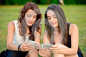 Two beautiful young women looking at smart phones