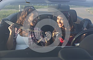 Two beautiful young women putting on seatbelt while smiling