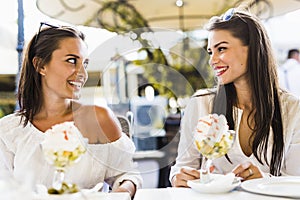 Two beautiful young women smiling and having a fruit salad in a